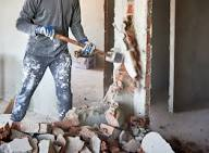 Demolition — worker with sledgehammer breaking down a wall